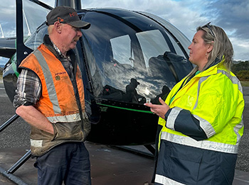 Two people talking beside a helicopter