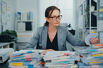 Woman with piles of paper.
