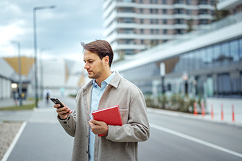 Guy looking at phone, carrying red book 