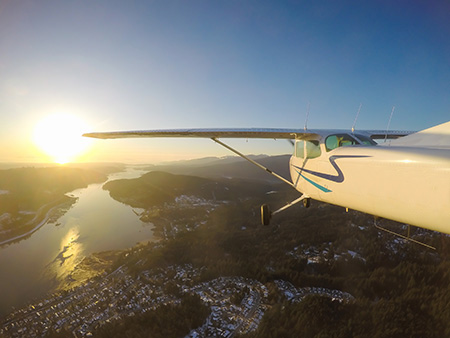 Fixed wing plane flying toward the sunset