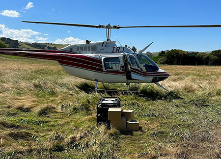 Helicopter on grass, with boxes of supplies to the side.