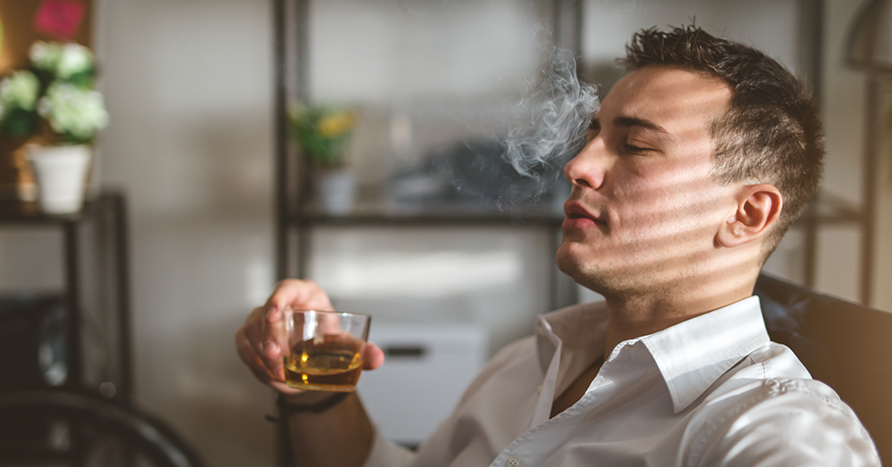 Man drinking whisky and smoking something