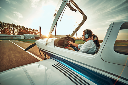 Man and woman in small plane on runway with top open