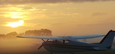 Fixed wing plan on ground with sunset in the background.