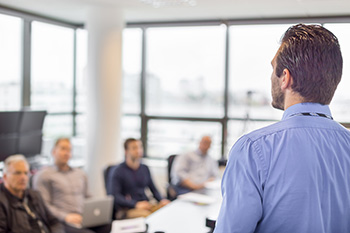 Man standing in office talking to seated colleagues